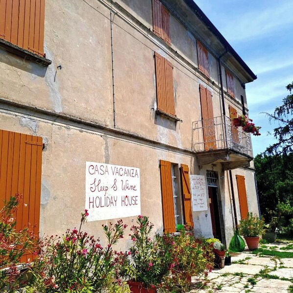 Un immeuble de deux étages sur lequel on peut lire l’inscription : « CASA VACANZA, maison de vacances où vous pourrez vous reposer et déguster du vin ».
