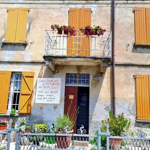 Stunning two-story building with a charming balcony featuring potted plants and a sign indicating the business name.