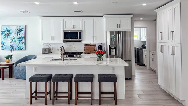A modern kitchen with white cabinets, a central island with stools, a microwave, a refrigerator, and a water dispenser. - 664 Naples Beach Paradise-Your Next Vacation Spot with Private Pool & Spa (Naples)