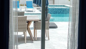 A room with a view of a swimming pool, wicker furniture, and a table. - 664 Naples Beach Paradise-Your Next Vacation Spot with Private Pool & Spa (Naples)