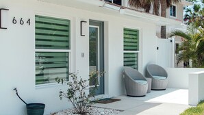 A modern house with a number 664, large windows, and outdoor wicker chairs. - 664 Naples Beach Paradise-Your Next Vacation Spot with Private Pool & Spa (Naples)