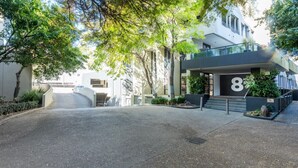 A modern building with a prominent number '8' on the facade, a gated entrance, and a well-maintained driveway.