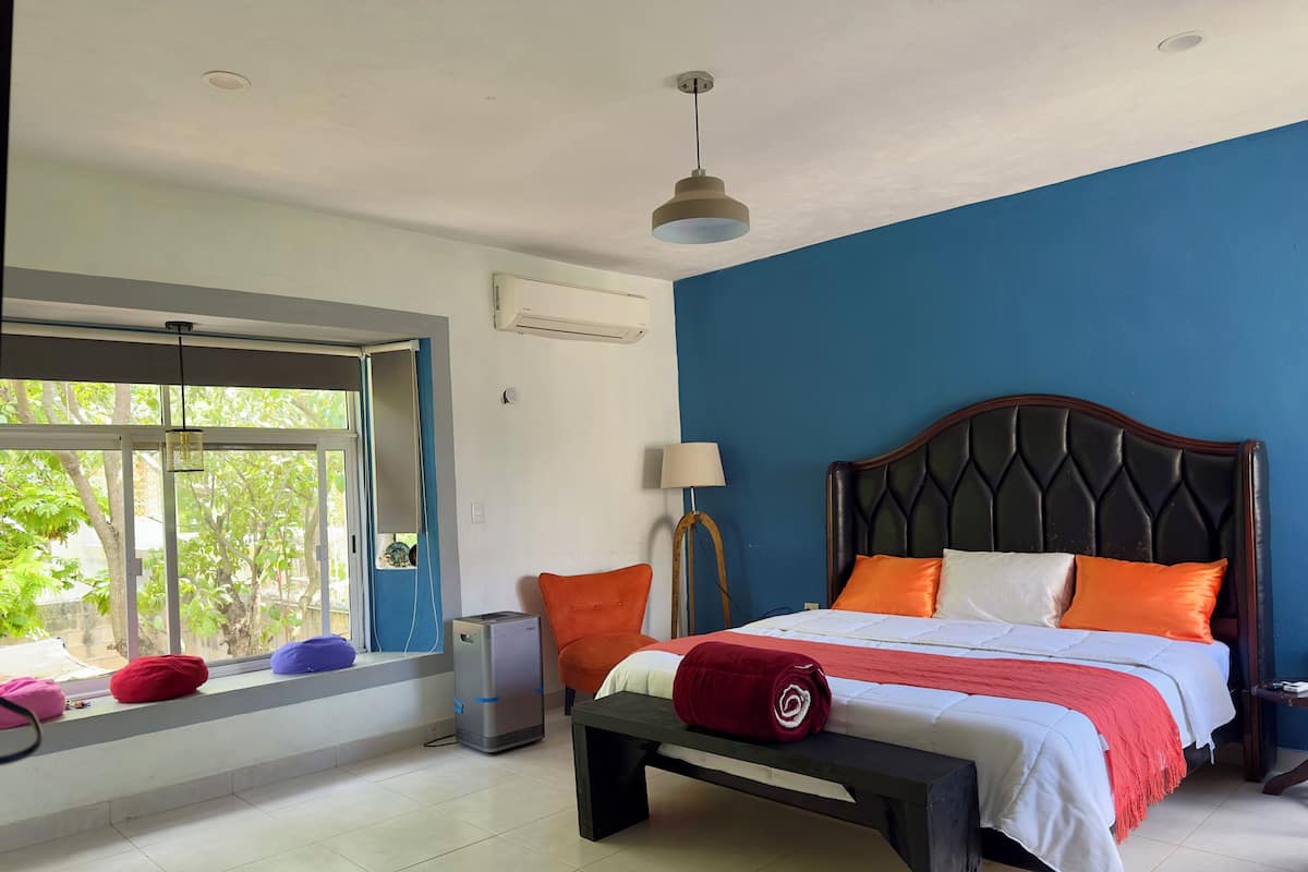 Un dormitorio con cama, ventana, escritorio y lámpara.