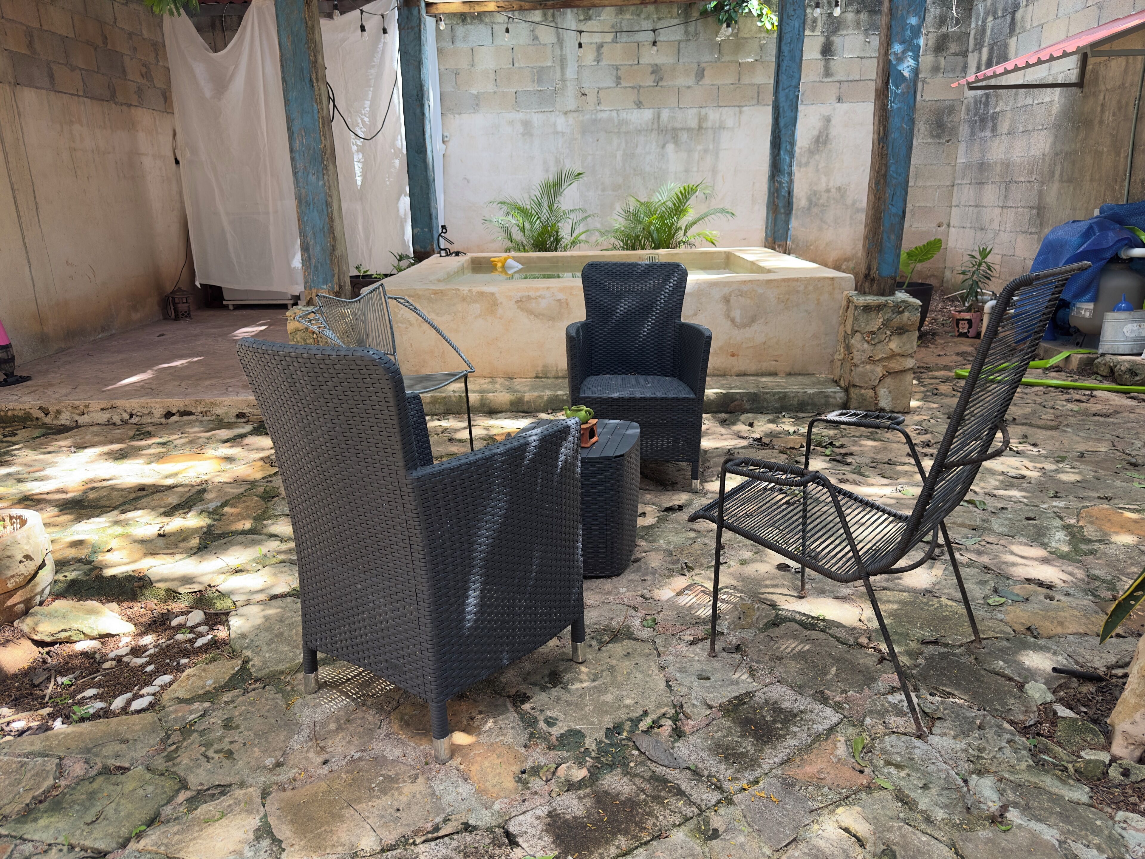 An outdoor seating area with wicker furniture, a small water feature, and potted plants.