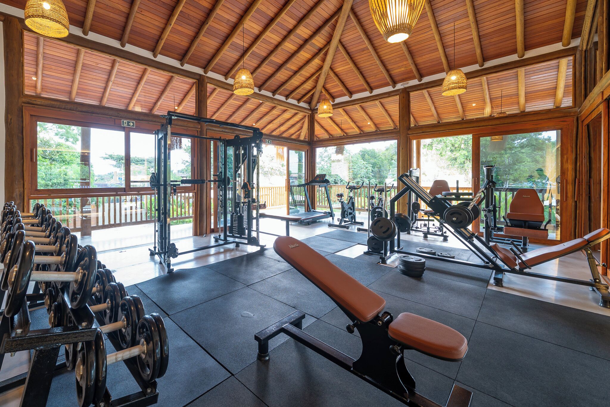Una palestra con attrezzature per esercizi, ampie finestre e soffitto in legno.