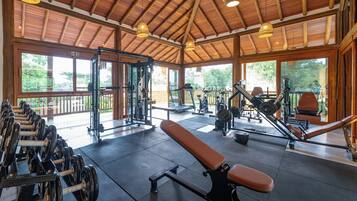 Una palestra con attrezzature per esercizi, ampie finestre e soffitto in legno.