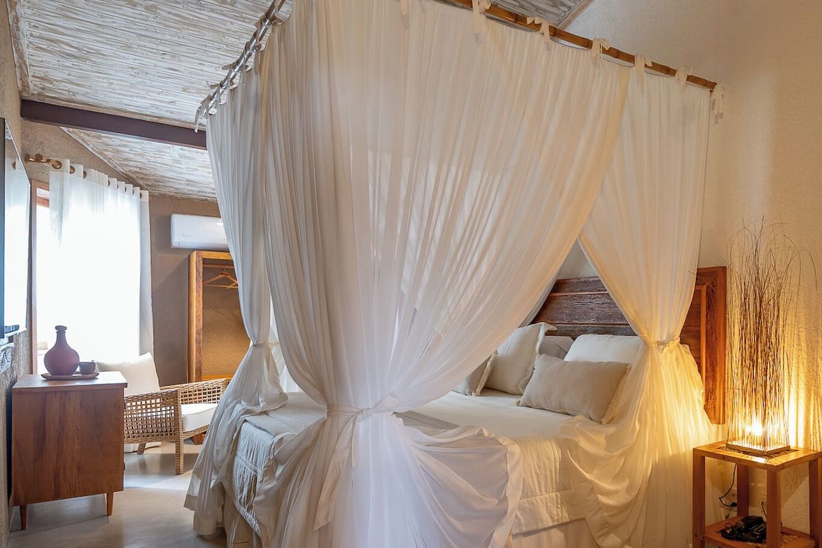 A room with a bed, a nightstand, a wooden chair, and a small table.