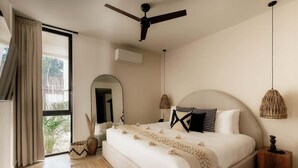 Un dormitori amb un llit gran, un ventilador de sostre, una finestra amb cortines i una làmpada penjant.
