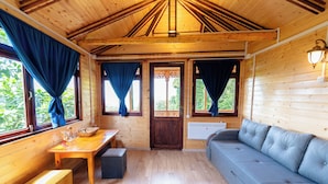 A wooden cabin interior with a sofa, table, and curtains.
