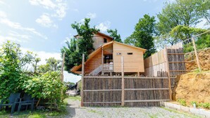 A wooden cabin with a balcony, surrounded by a wooden fence and trees.