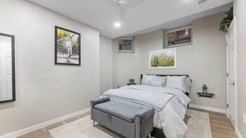 A bedroom with a bed, a bench, a ceiling fan, and framed pictures on the wall.