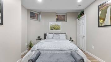 A bedroom with a bed, bedside tables, a bench, a window, and a door.