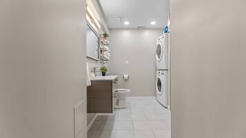 Ein modernes Badezimmer mit Toilette, Waschbecken und übereinander angeordneter Wasch- und Trockenmaschine.