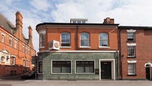 Un edificio en esquina con fachada verde y un cartel que dice 'Foyer Green'.
