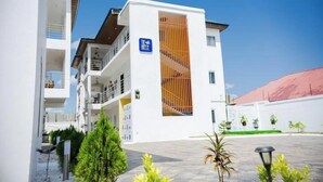 A modern multi-story building with balconies, a staircase, and a sign indicating a hotel. - Peaceful Escape in Tema Community 25 (Dawhenya)