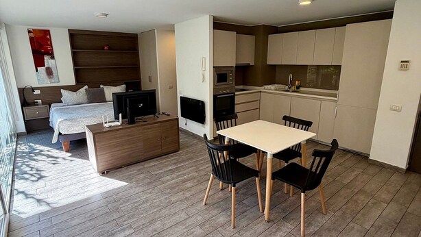 A modern apartment with a dining area, kitchen, and a bedroom. - Moderno y equipado estudio en Los Dominicos (Santiago)