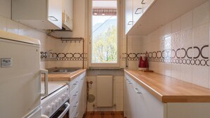 Una cocina estrecha con armarios blancos, una estufa blanca y una encimera de madera.