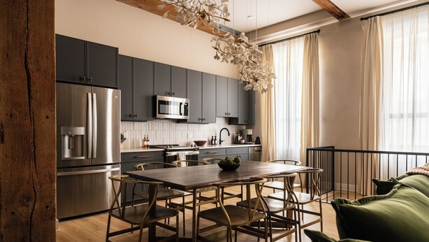 A modern kitchen with dark cabinets, stainless steel appliances, and a wooden dining table with chairs. - The Artisan's Duplex - 8Bd/5.5Bth w/2 Car Parking! (Philadelphia)