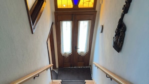A staircase with wooden steps and a handrail, leading to a door with a stained glass window above it. - Hera Pansiyon (Ayvalik)