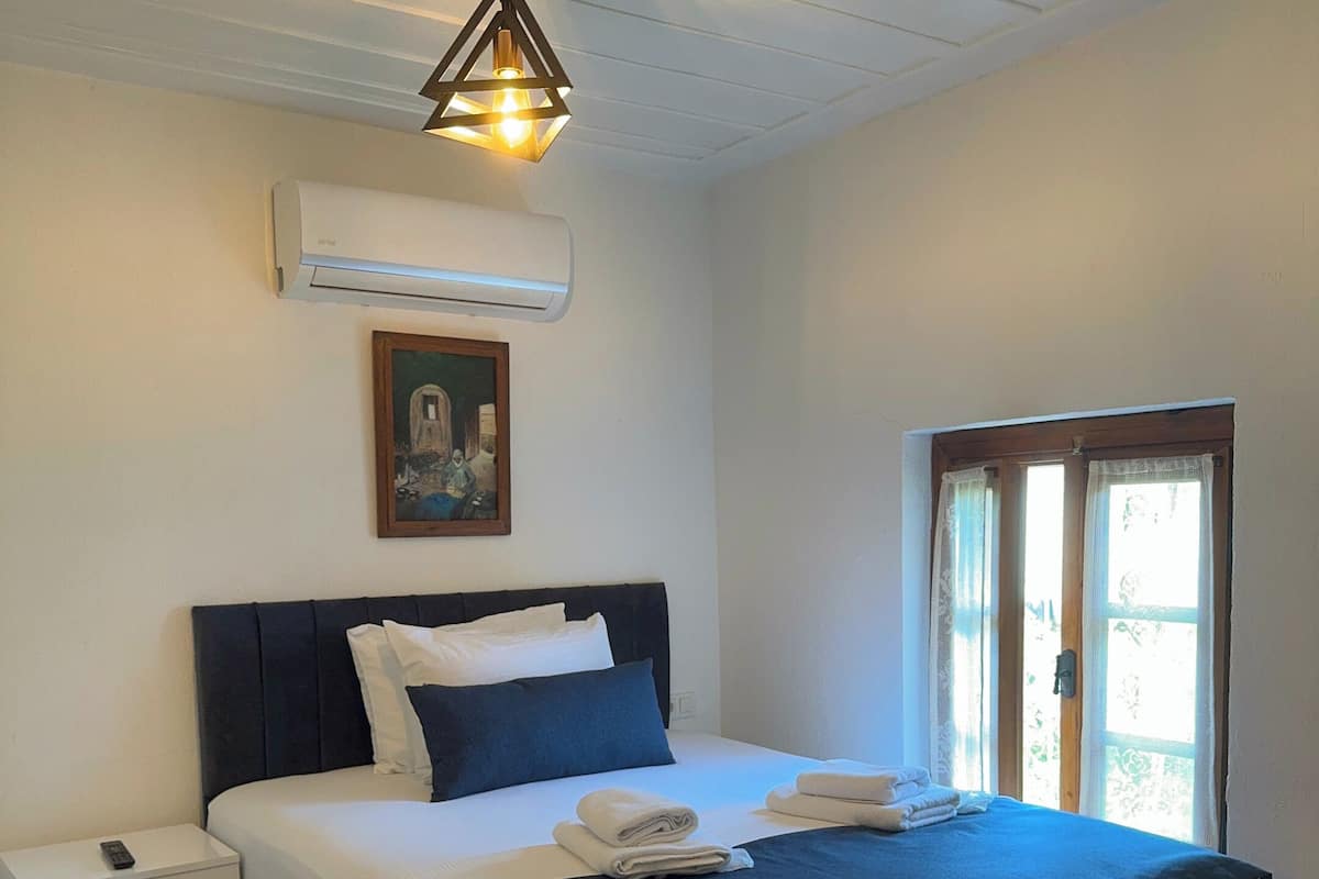 A bedroom with a bed, bedside table, and a window.