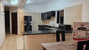 A modern kitchen with a black countertop, stainless steel appliances, and a tiled backsplash.