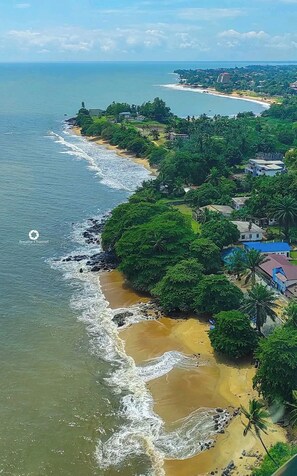 A coastal area with a beach, greenery, and buildings. - Chambres Bohèmes (Kribi)