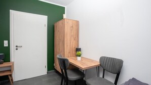 Een kleine kamer met een houten tafel, twee stoelen, een witte deur en een groene muur.