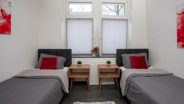 Een slaapkamer met twee bedden, een klein tafeltje en een radiator.