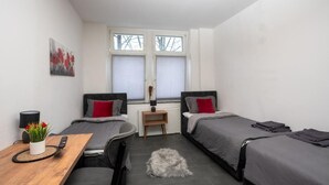 Een moderne slaapkamer met twee bedden, een bureau en een klein tafeltje.