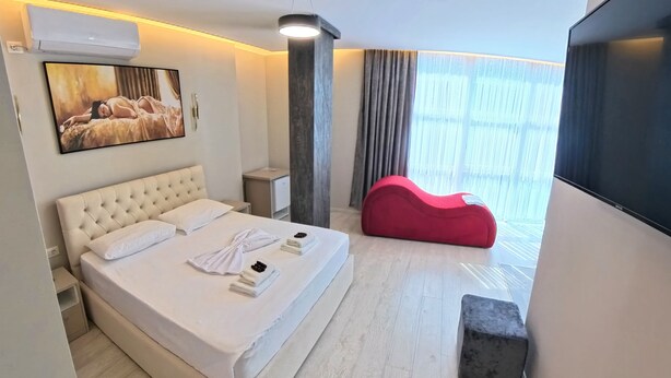 Ein Hotelzimmer mit einem Bett, einem roten Sitzsack, einem Flachbildfernseher und einem Bild an der Wand.