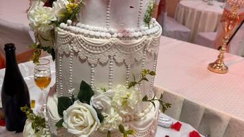 A multi-tiered cake with white icing and floral decorations, placed on a table with a white tablecloth.