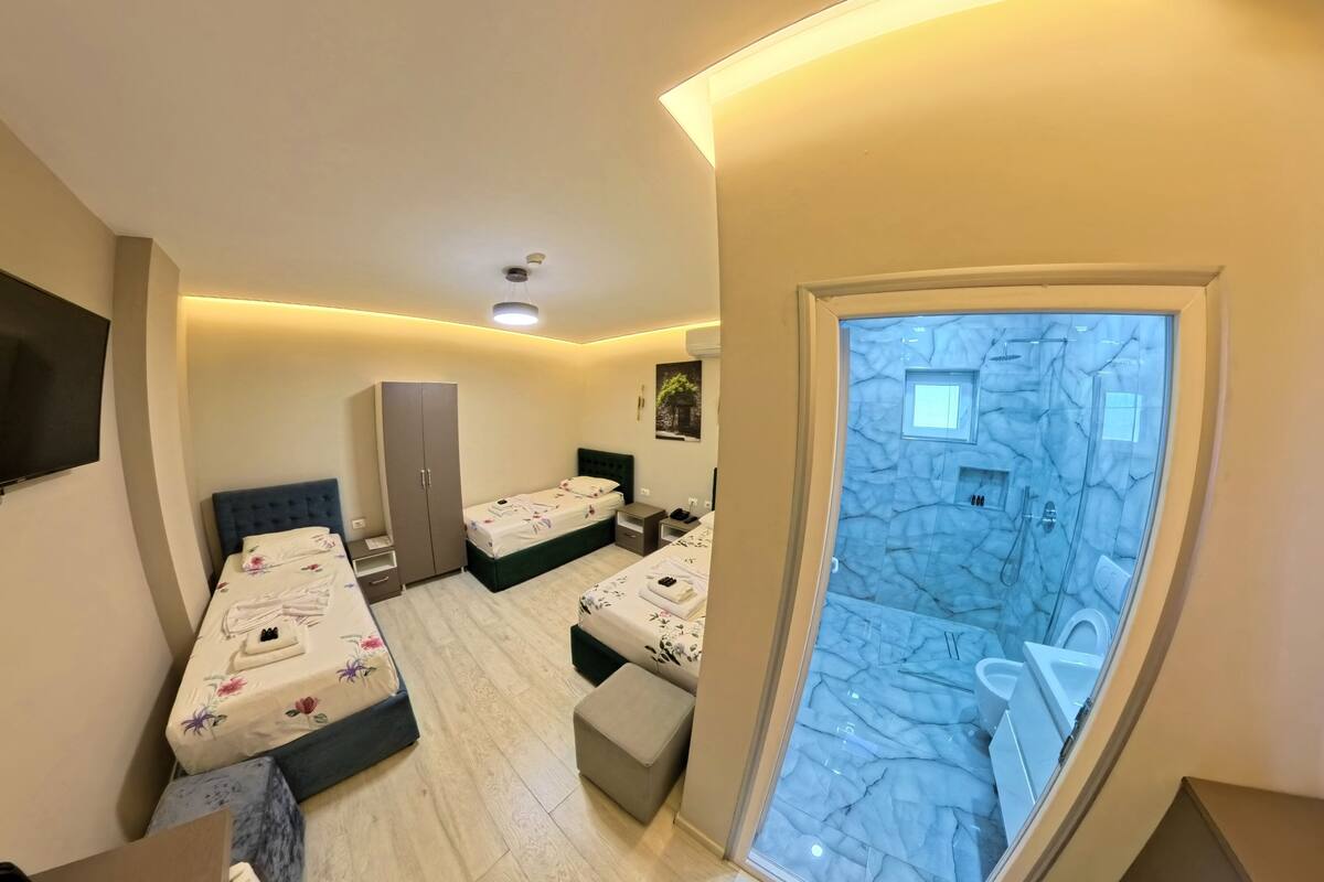 Un dormitorio con dos camas, un armario, un televisor y un baño con piso de mármol.