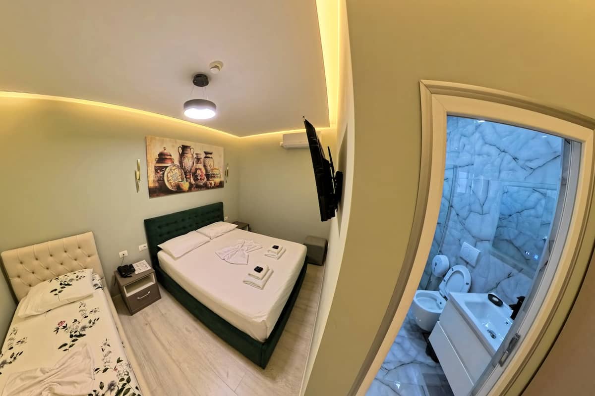 A bedroom with a bed, bedside table, and a painting on the wall.