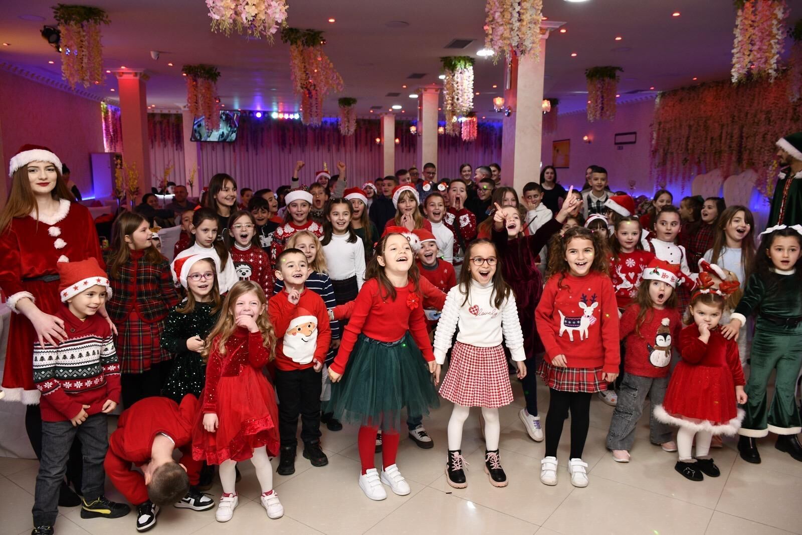 Un grupo de niños con ropa festiva posando para una foto en un espacio interior decorado.