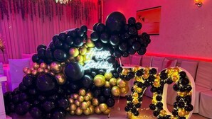 Ein Zimmer mit einer großen Ballon-Dekoration aus der 70er und einem Schild mit der Aufschrift 'Happy Birthday', das auf eine Feier hindeutet.
