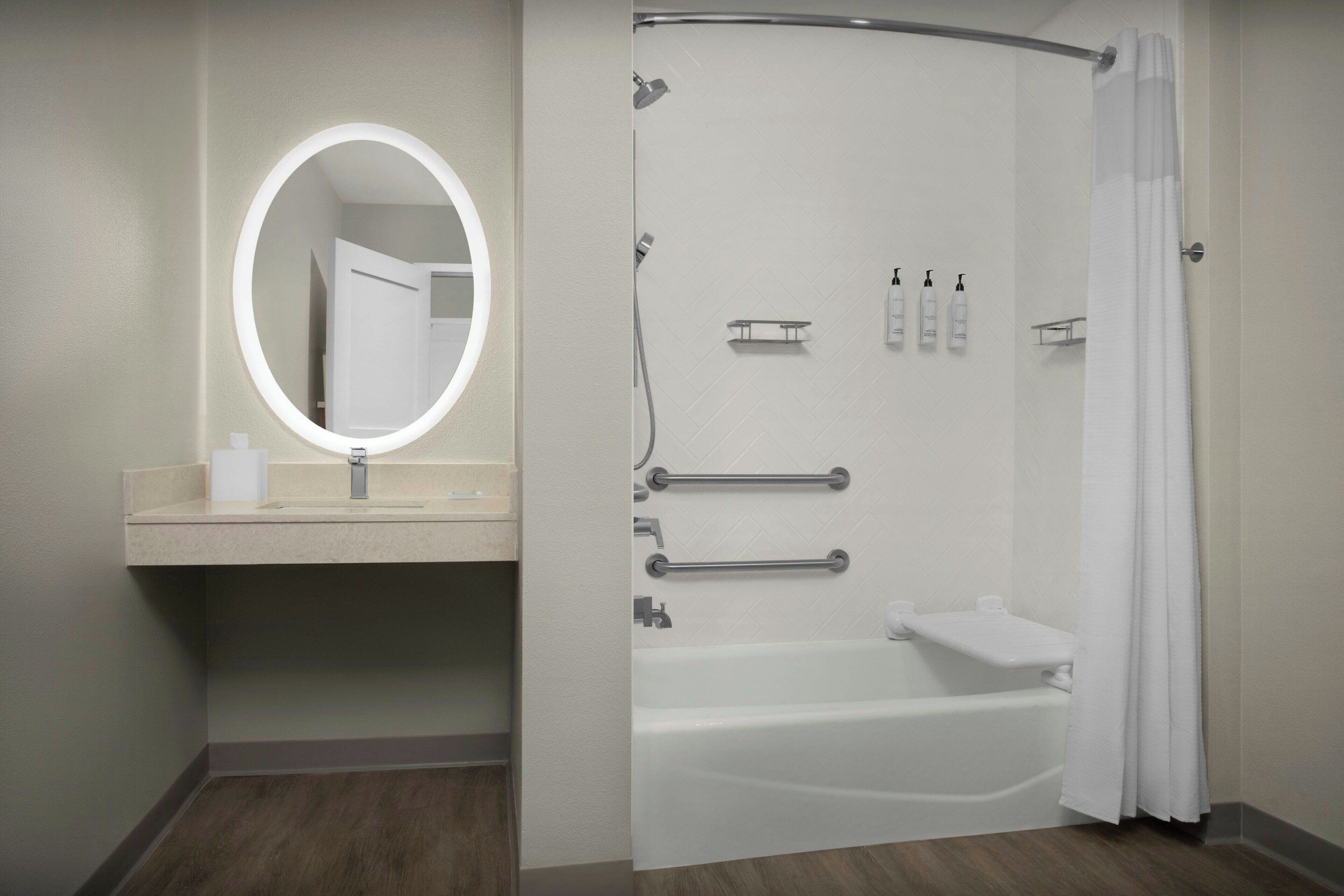 A modern bathroom with a round mirror, a bathtub, and a shower area.