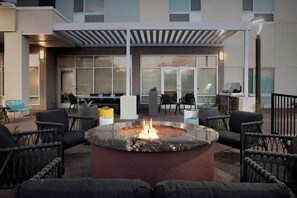 An outdoor seating area with a fire pit, wicker chairs, and a covered patio. - Towneplace Suites El Paso Northwest (El Paso)