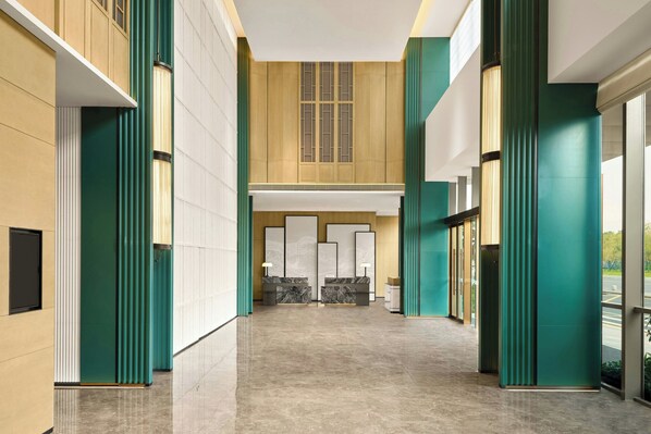 A spacious lobby with a high ceiling, a marble reception desk, and large windows allowing natural light. - Courtyard Shunde (Foshan)