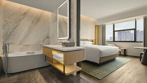 Ein modernes Hotelzimmer mit Marmorwand, einem großen Bett, einer Sitzecke und Blick auf die Stadt.