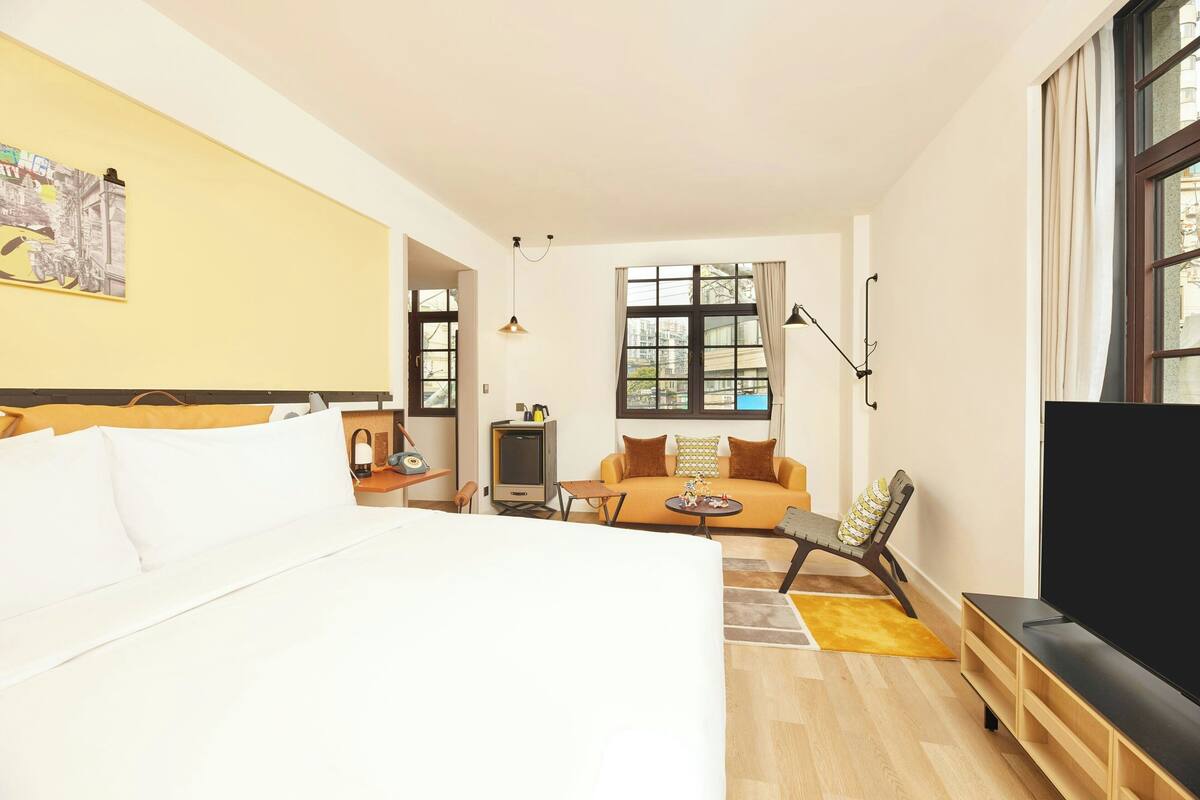 A hotel room with a large bed, a sofa, a TV, and a desk.