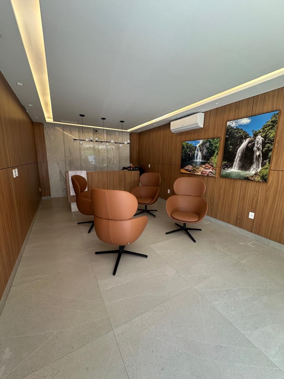 A modern waiting area with wooden paneling, a reception desk, and three brown chairs.