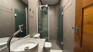 Un baño moderno con ducha de vidrio, lavabo blanco y retrete.
