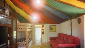 A cozy room with bunk beds, a red sofa, a television, and a small table with a plant. - House of Artists (Xullán)