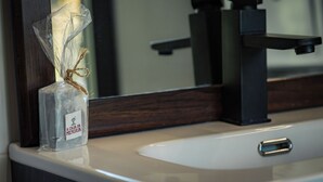 A clear glass bottle with a label on a bathroom counter. - House of Artists (Xullán)