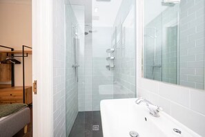 A modern bathroom with a glass shower enclosure, a white sink, and a wooden bench. - Cosy Retreat for Two off Upper St, Islington - Pass the Keys (London)