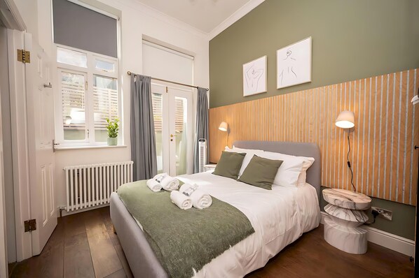 A neatly made bed with a green throw, a bedside lamp, and a wooden panel wall. - Cosy Retreat for Two off Upper St, Islington - Pass the Keys (London)