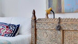 A bed with a wooden headboard featuring intricate carvings, a white pillow, and a colorful throw blanket. - Pass the Keys | Charming Ground Floor Flat with Free Parking (Cambridge)