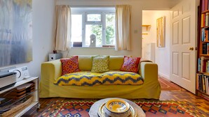 A room with a yellow sofa, a patterned rug, a white door, and a bookshelf. - Pass the Keys | Charming Ground Floor Flat with Free Parking (Cambridge)