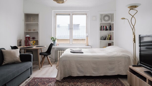 Une chambre à coucher moderne comprenant un lit, un bureau, une chaise, un canapé, un téléviseur et une bibliothèque.