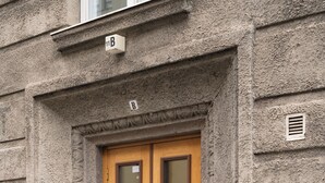Un bâtiment doté d’une façade en pierre, d’une porte double en bois avec des panneaux de verre et d’une petite enseigne au-dessus de la porte.